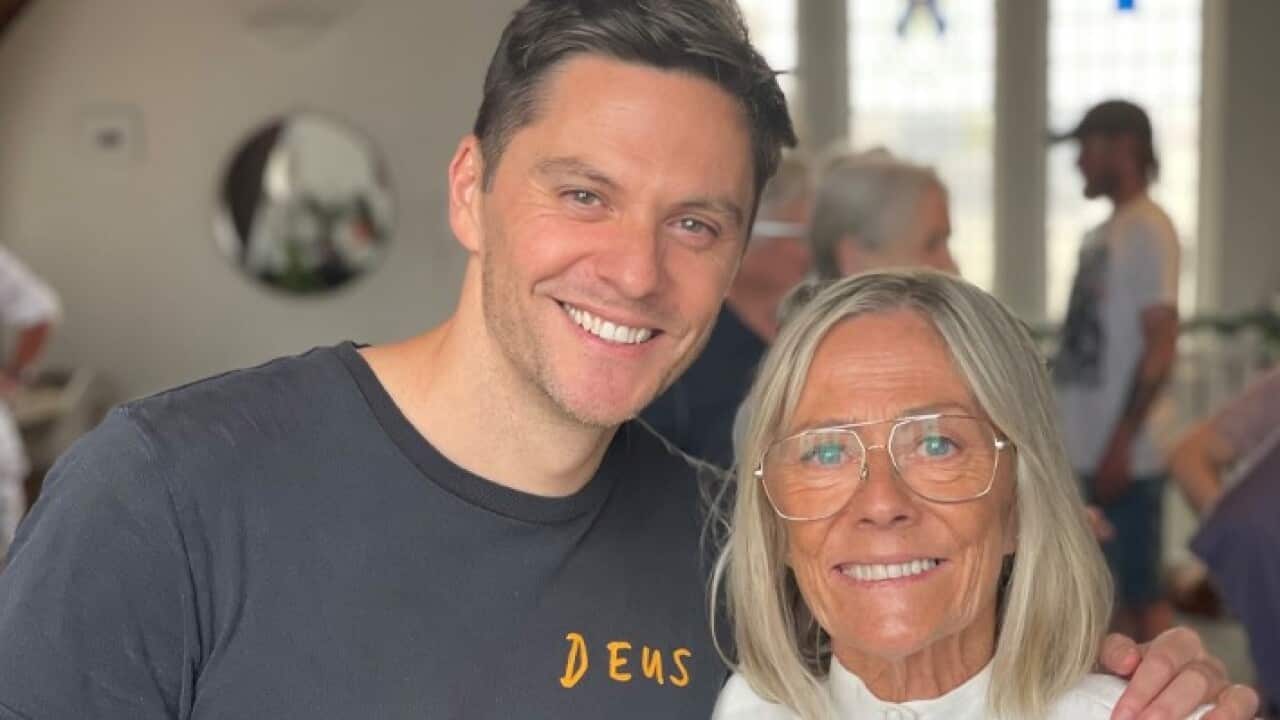 Rien and his mother smiling at the camera with their arms around each other.