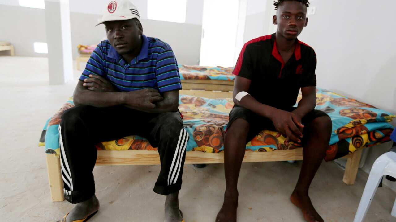 An unidentified Malian survivor, right, of a shipwreck sits in the Red Crescent center of Zarzis, southern Tunisia.
