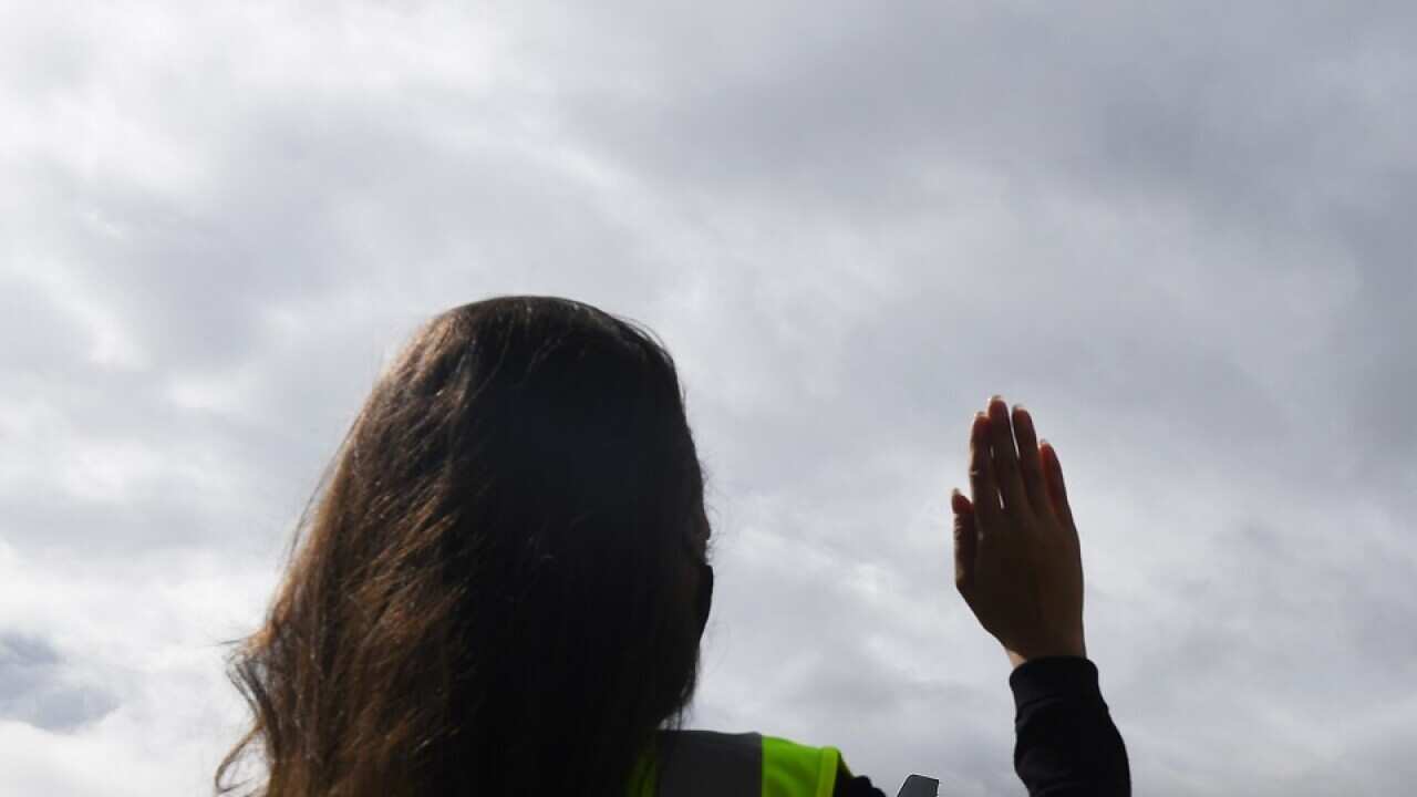 A Melbourne Airport staff member waves to a pilot in a Sydney-bound Jetstar plane at Melbourne Airport on 23 November 2020.  