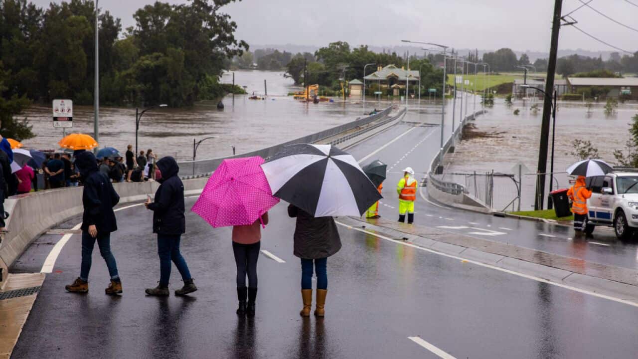 People look on as floodwater rises over the New Windsor Bridge on The Hawkesbury River in Windsor on 21 March, 2021 in Sydney.