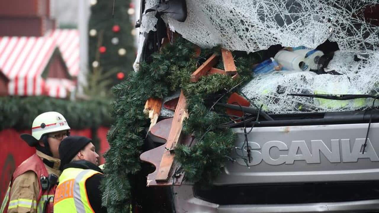 A police officer and fireman inspect a damaged truck on a road beside the Christmas market at Breitscheidplatz in Berlin, Germany, 20 December 2016. (DPA)