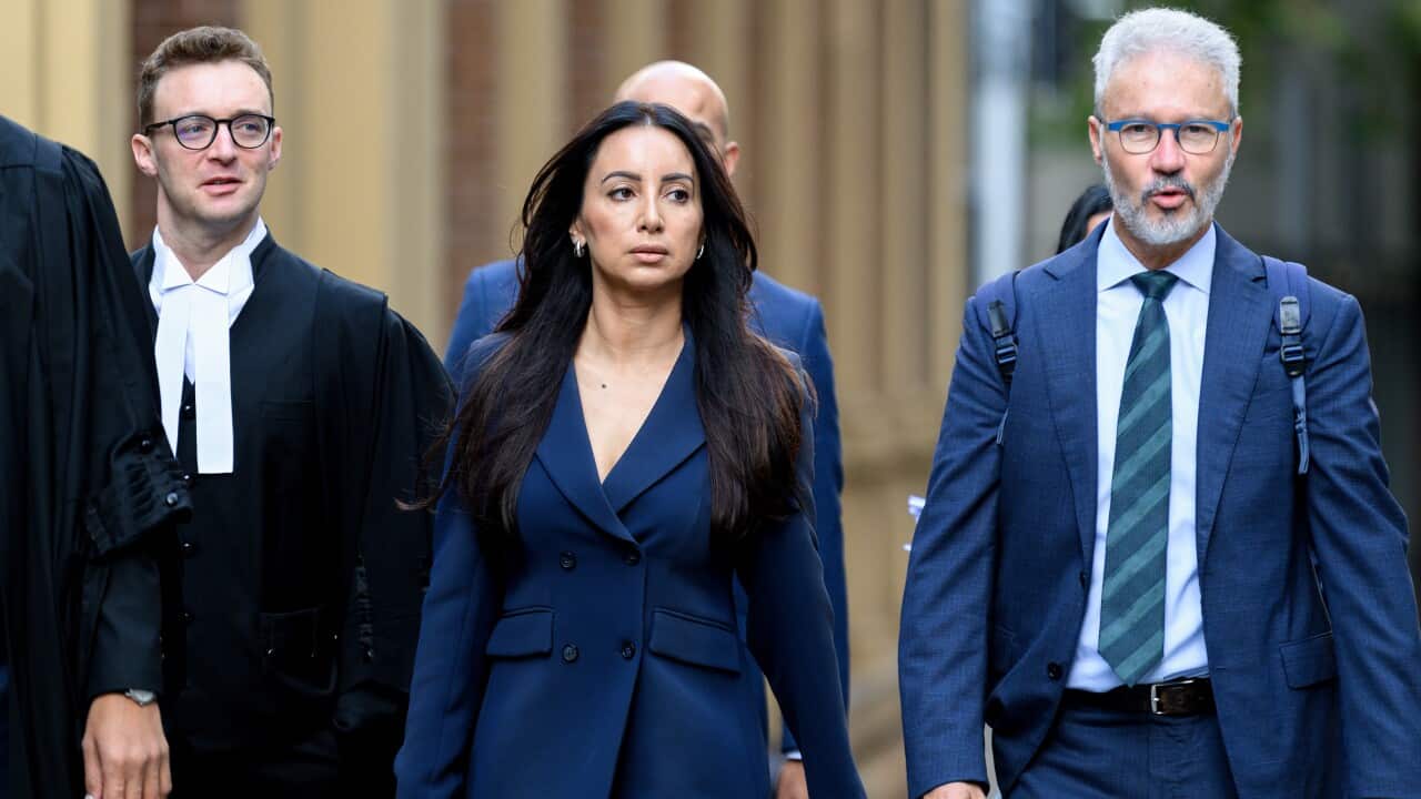 A woman in a dark blue blazer walks in the centre of a group of men
