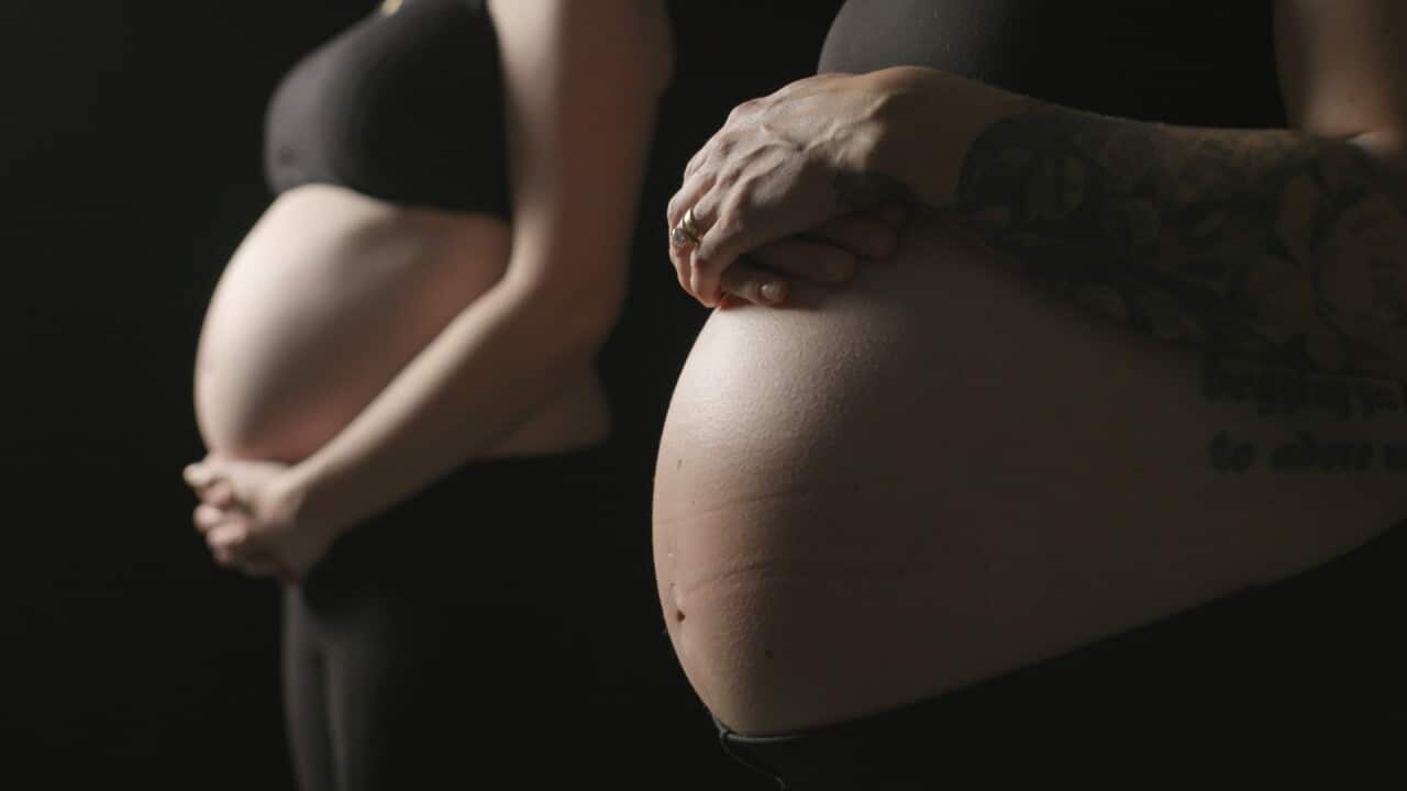 Two pregnant women posed with their bellies out.