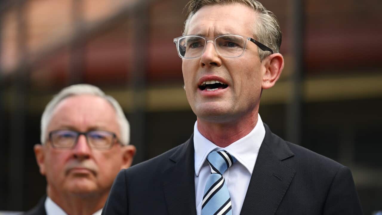 A man wearing a suit, tie, and glasses who is speaking.
