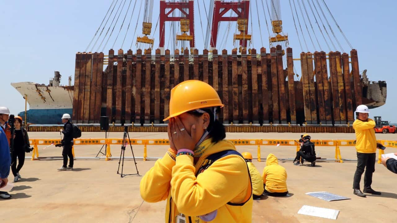 A family member of one of the victims of the Sewol ferry sinking weeps after the vessel is successfully lifted upright on May 10, 2018, at a port in Mokpo