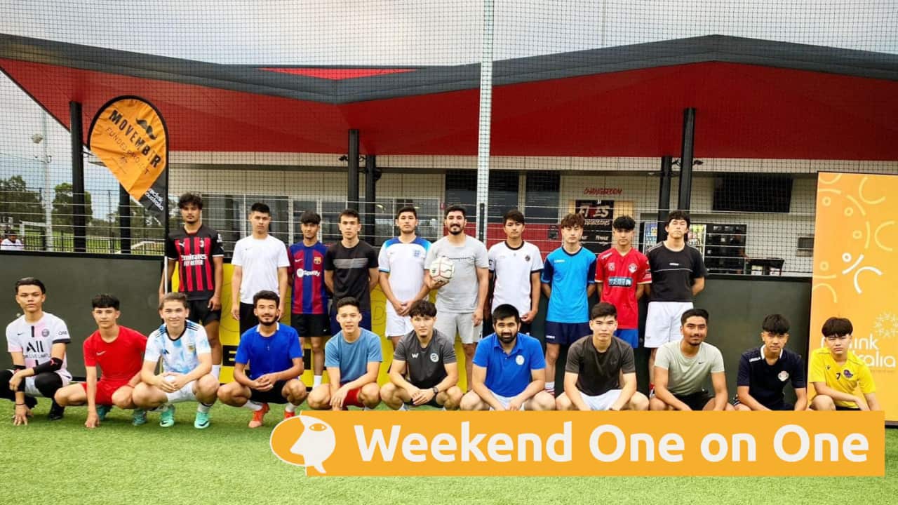 Roman Abasy (centre, back row) is pictured holding a football with participants of the sports program that he co-ordinates for non-profit Reclink Australia._supplied.png