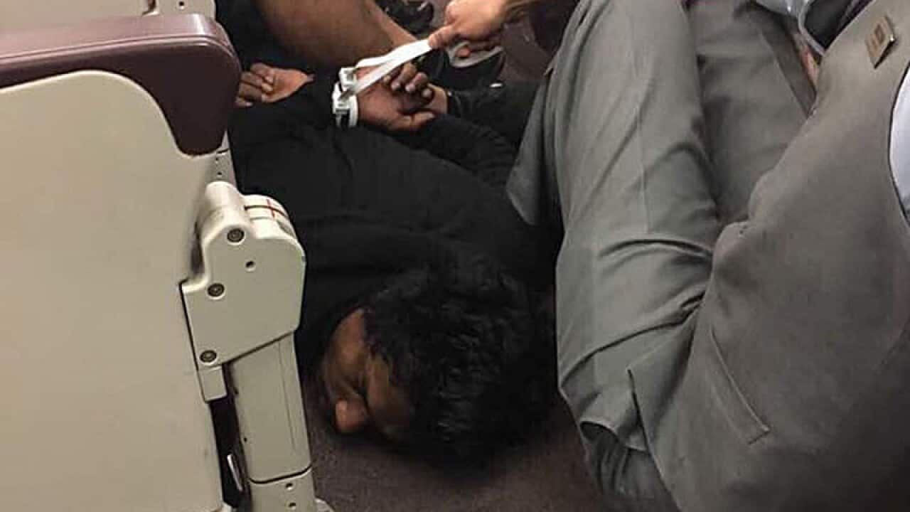 A man being detained after bomb threats