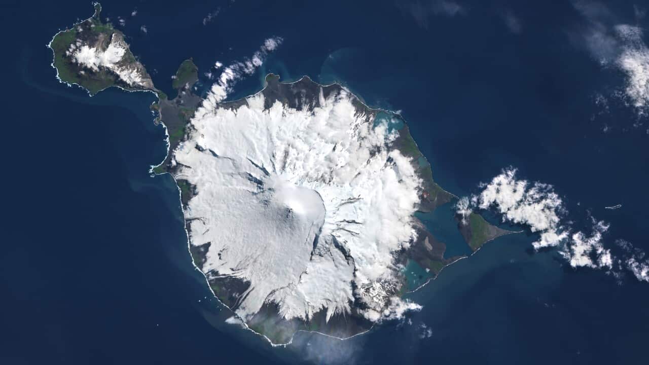 A satellite view of Heard Island. The island is encrusted with snow and surrounded by a deep blue ocean.
