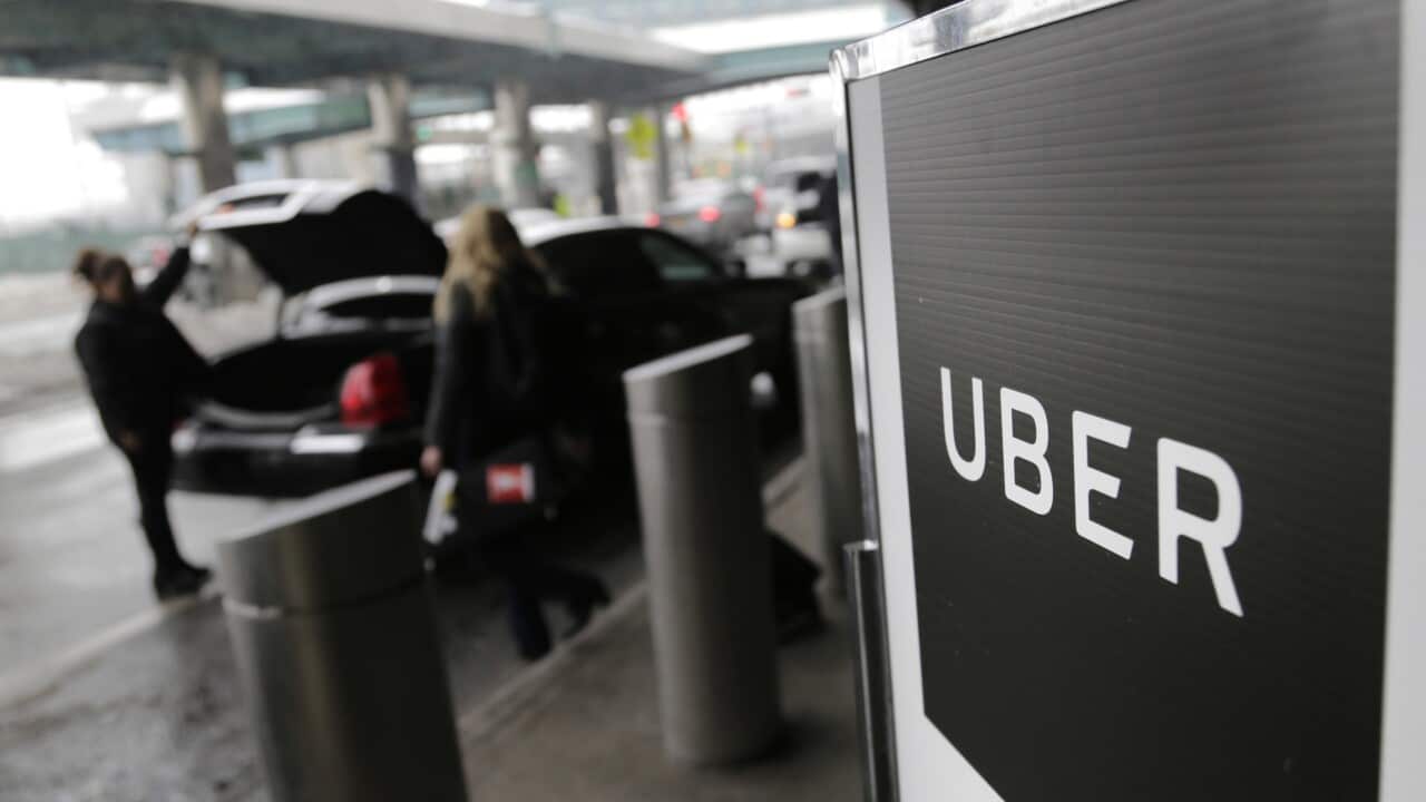 Two people getting into a car parked near a sign that reads: "UBER".