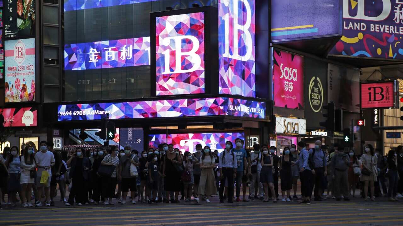 People wait to cross a street in Hong Kong.