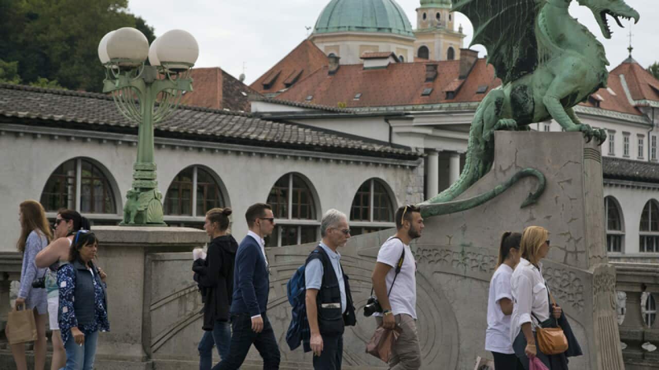 Tourists and residents walk past a statue in Ljubljana, Slovenia