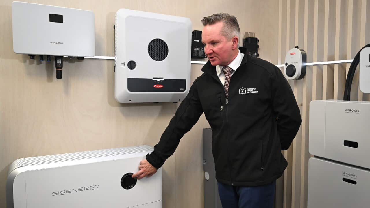 Chris Bowen standing in front of solar batteries.
