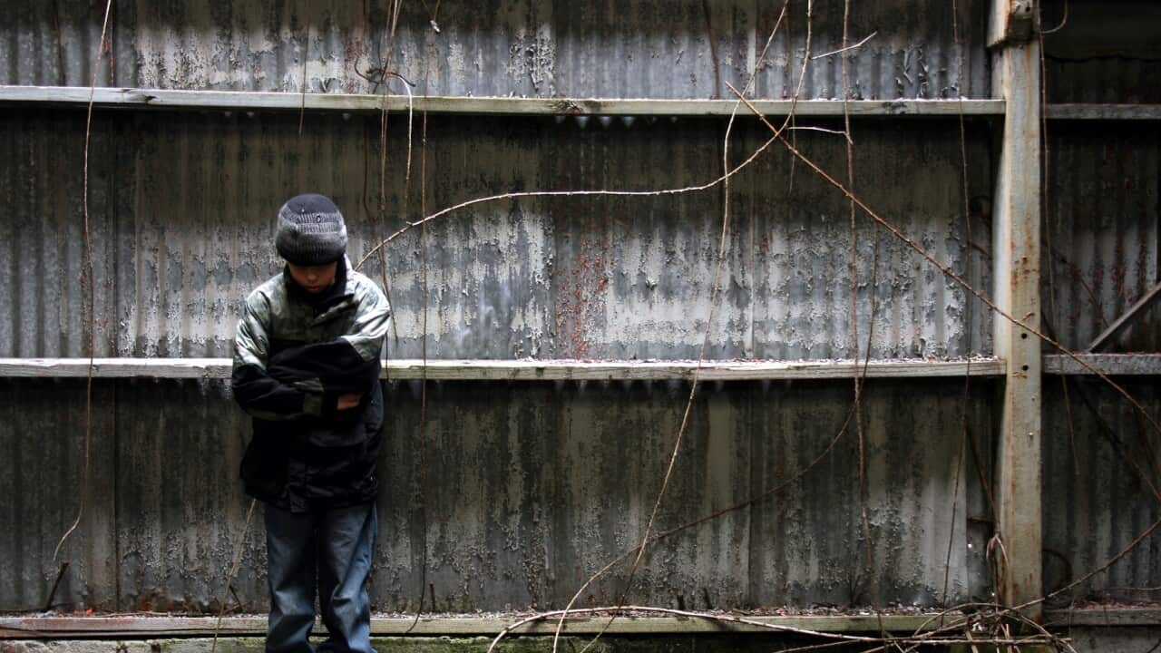 Boy Standing in Grunge Alleyway Against Abandoned Building