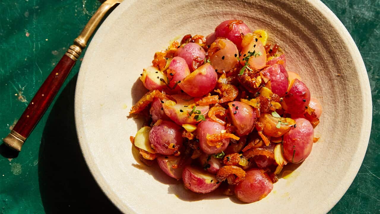 Pale pink radish halves sit in a round, cream-coloured bowl.