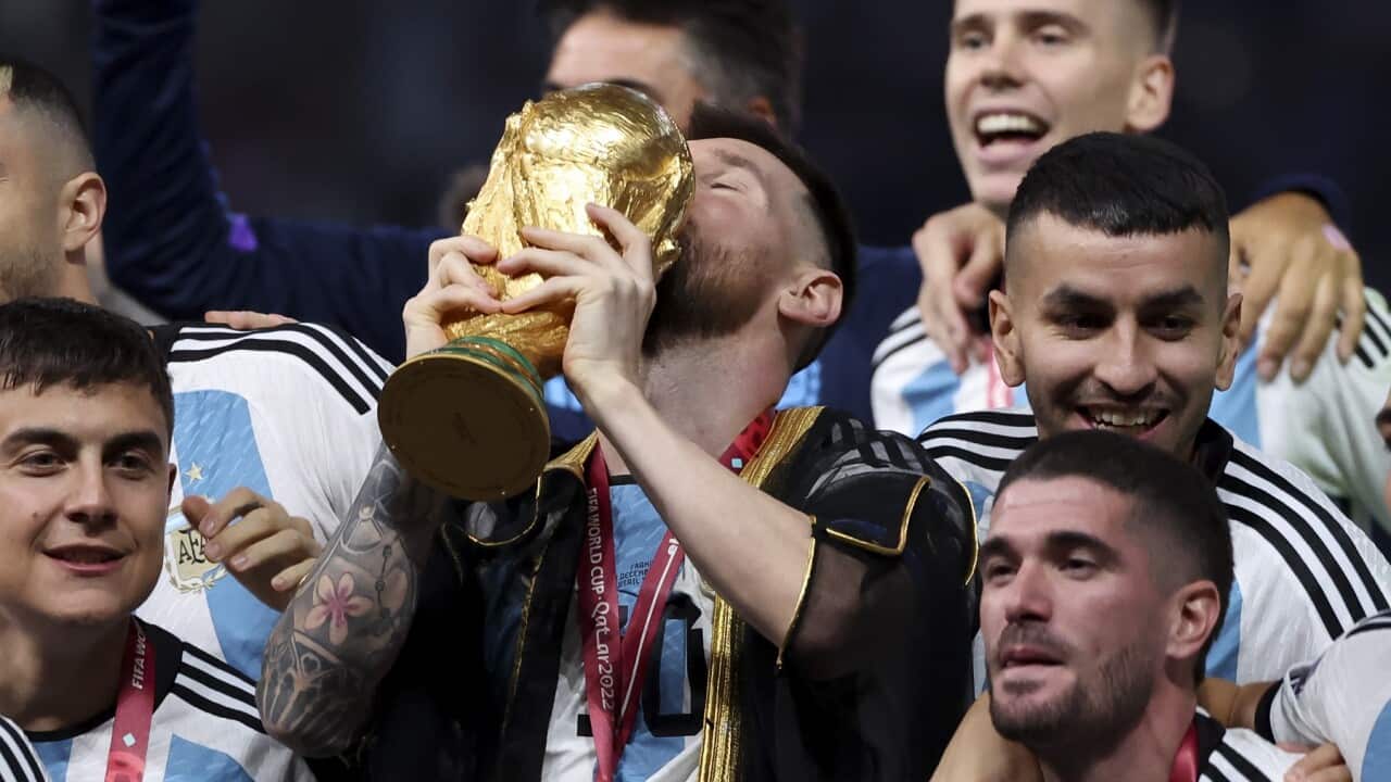 Lionel Messi of Argentina holding the World Cup and teammates celebrate