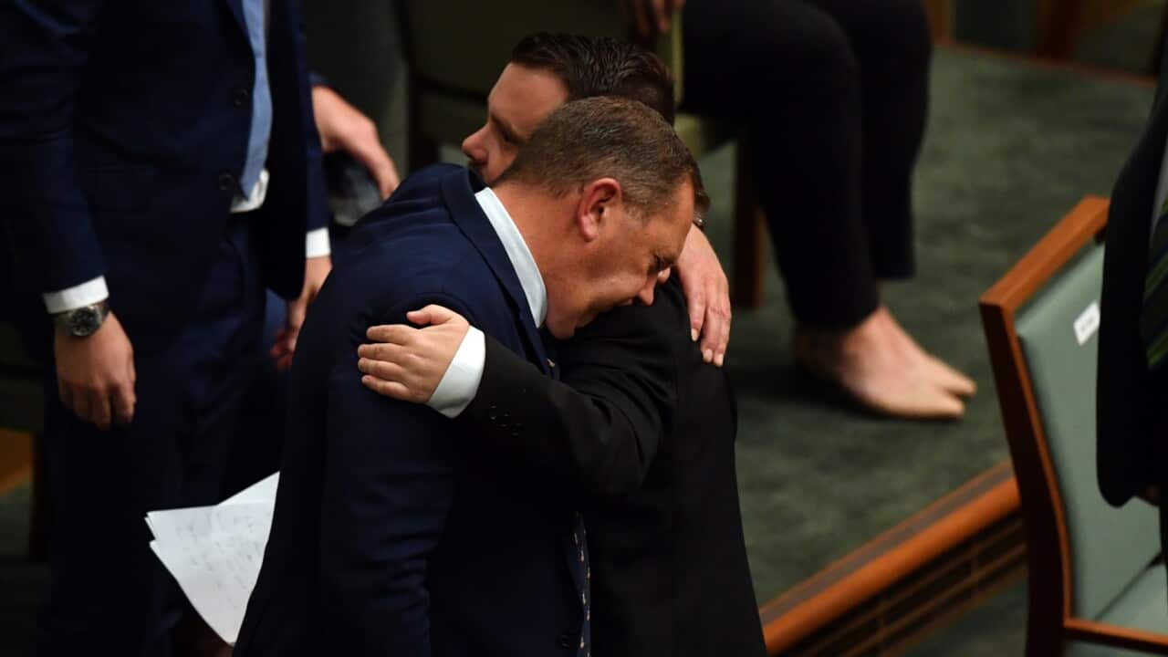 Liberal MP Phillip Thompson is hugged by colleague Gavin Pearce after speaking on veteran suicide