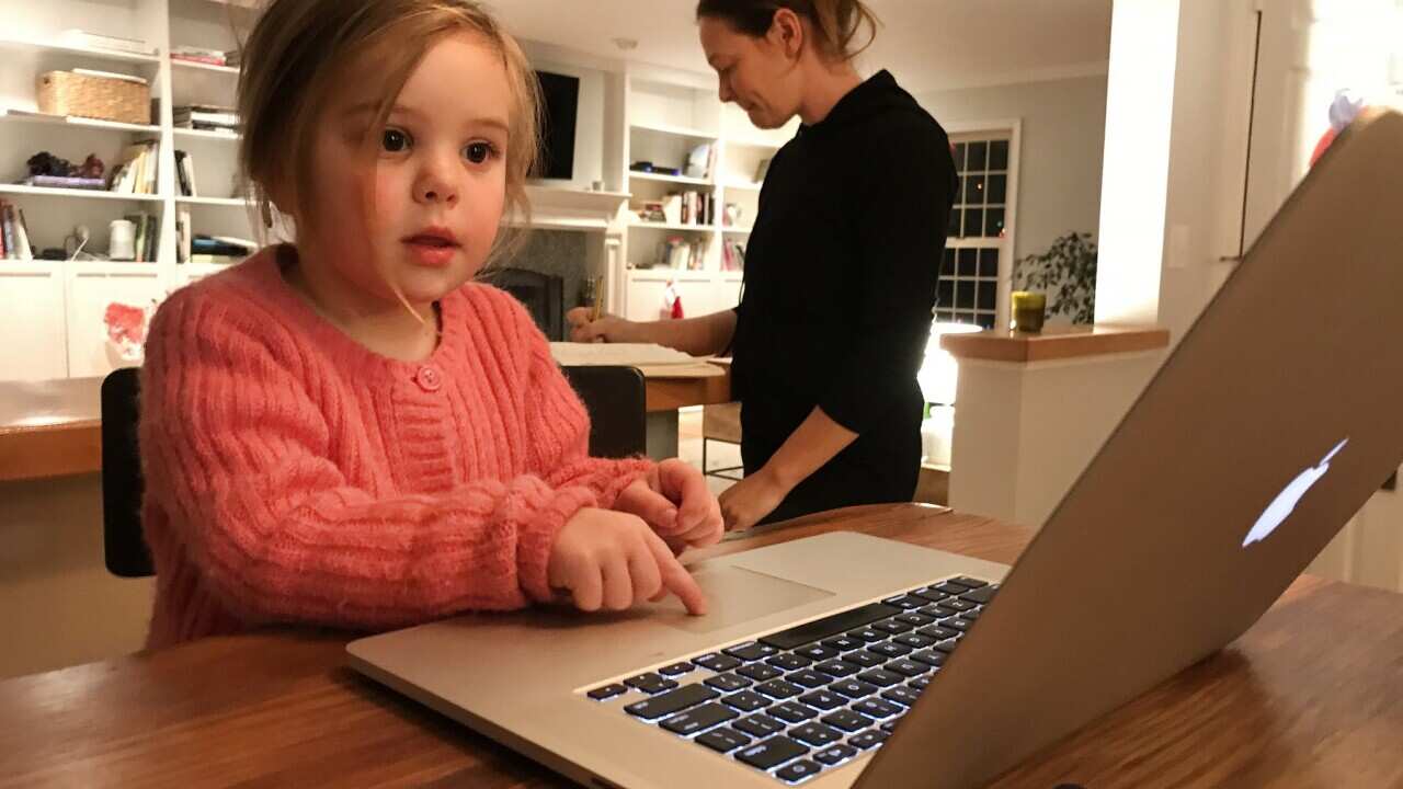 A three year old girl playing on an computer.