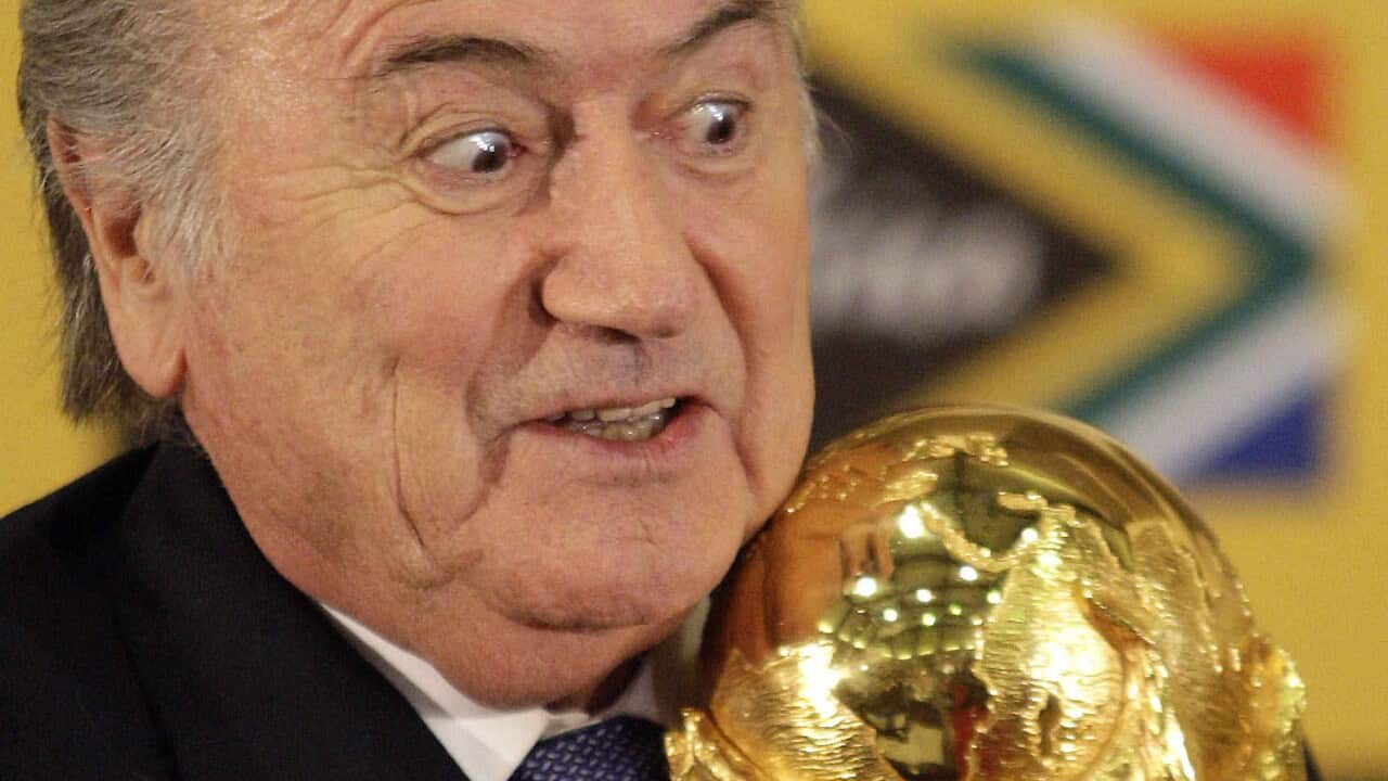 Joseph Blatter holds the trophy after receiving it back from South African President Jacob Zuma,