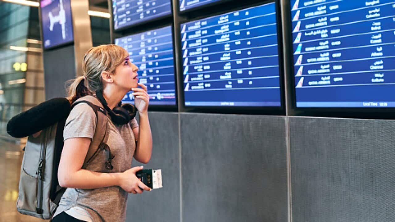 A young woman looking at the flight schedule in the airport.