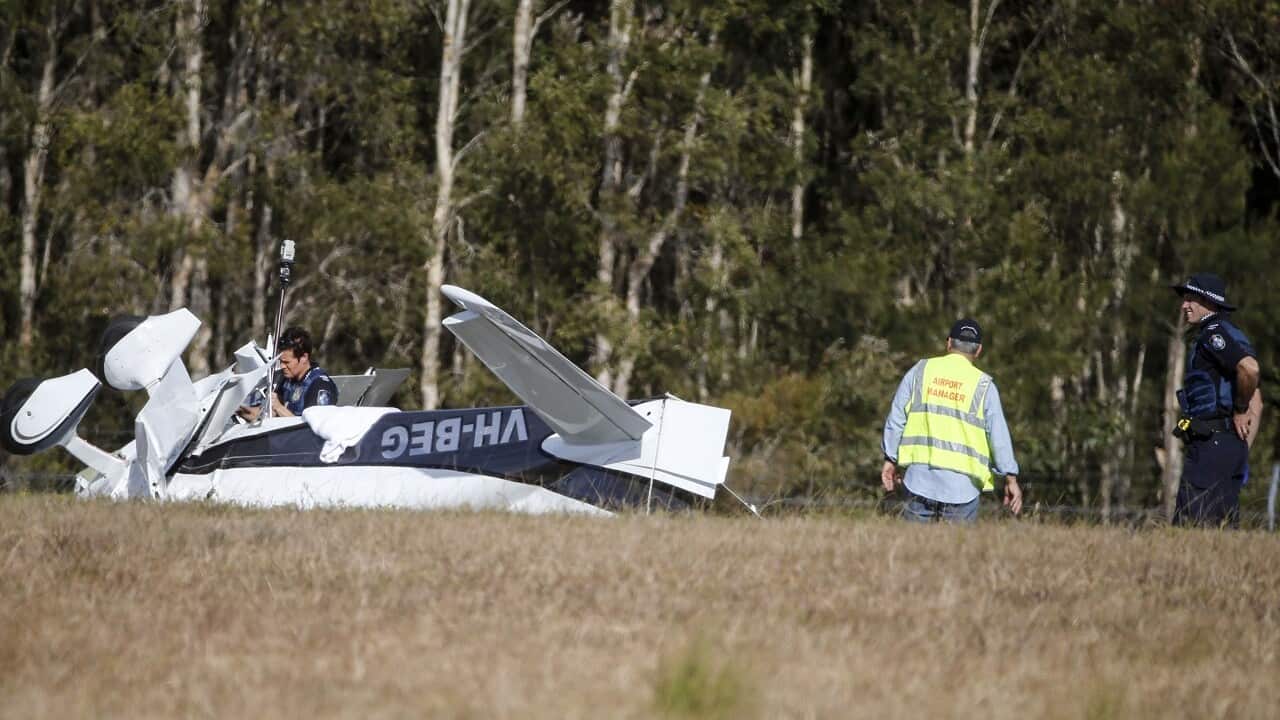 Police investigators examine a light plane that flipped at Caloundra Airport.