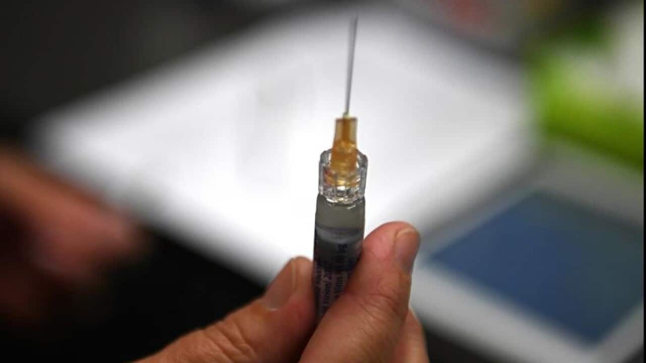 A hand holding a syringe