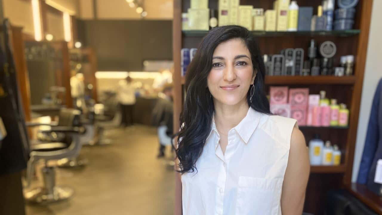 Woman standing near the entrance of her barber shop.