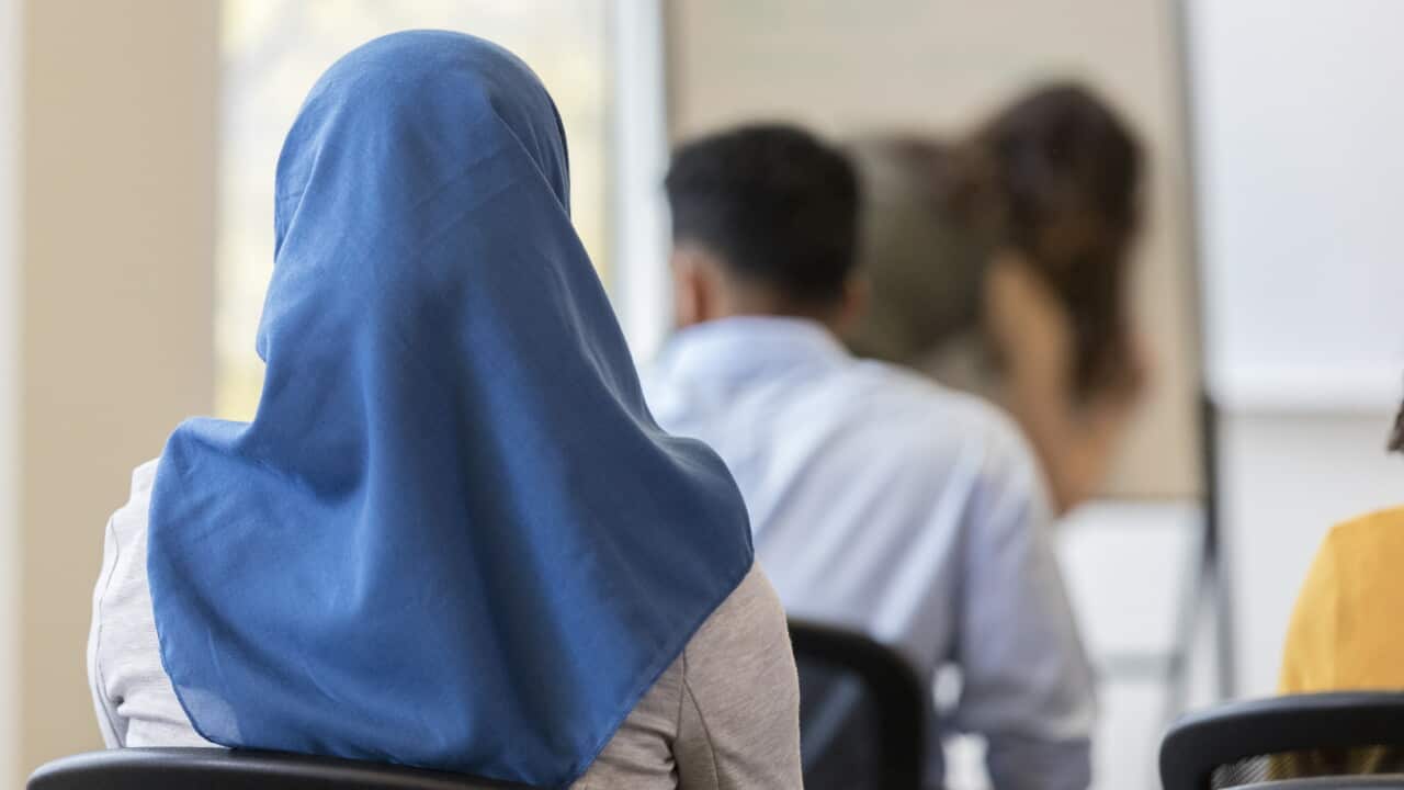 Rear view of woman wearing hijab sitting in classroom.