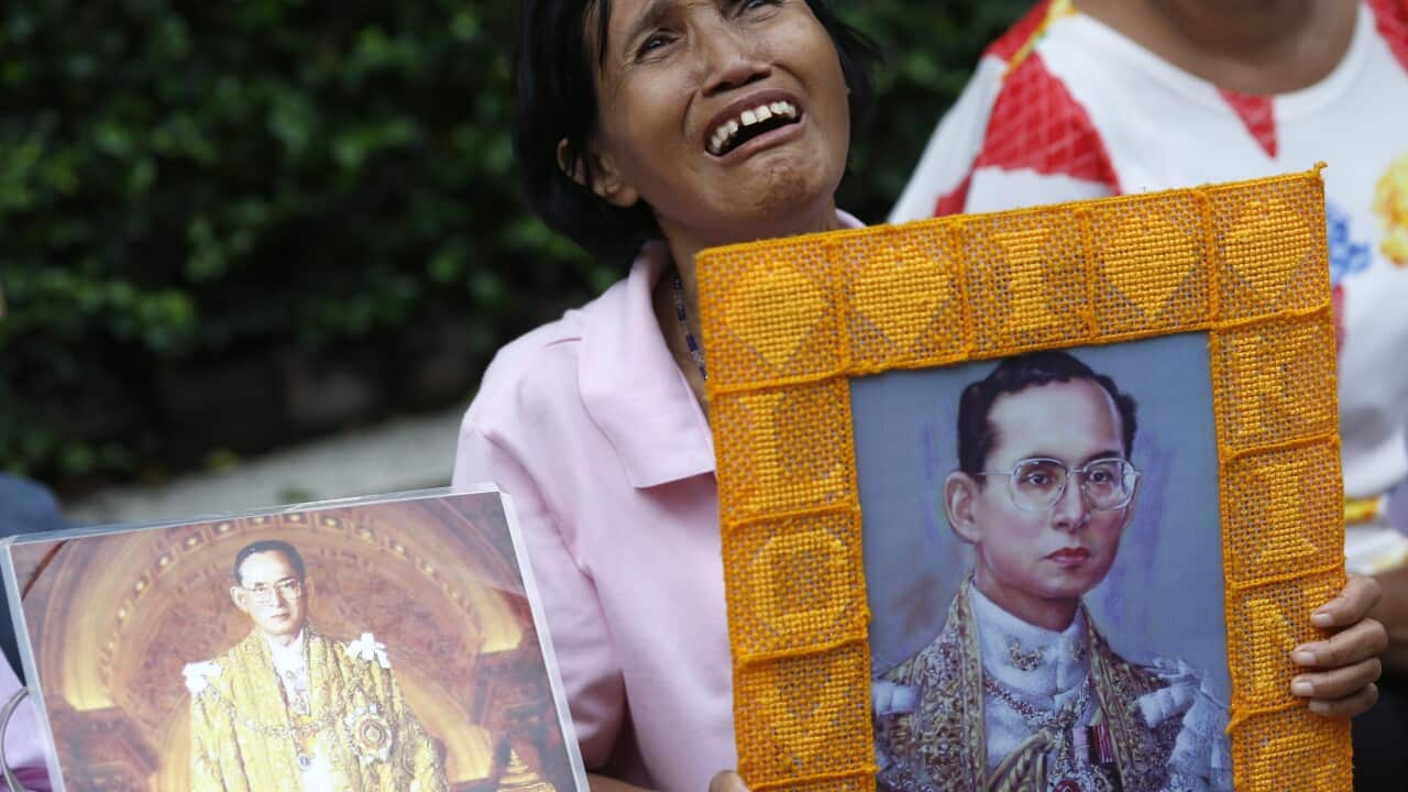 A Thai well-wisher cries behind portrait of Thai King Bhumibol Adulyadej as she prays and wishing health recovery for the king at Siriraj Hospital