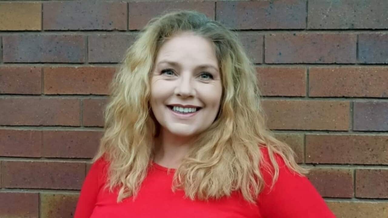 A woman with blonde hair and wearing a red jumper smiling
