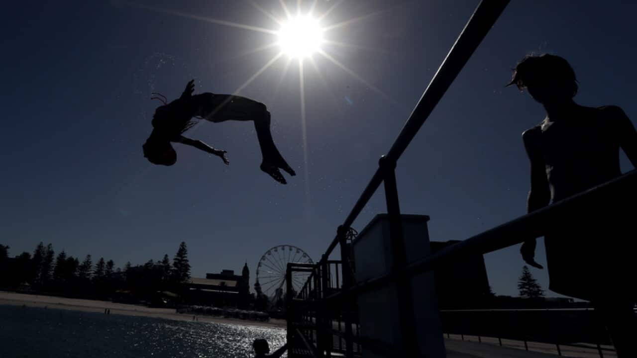 Beachgoers jumping off a jetty at Glenelg Beach during a heatwave in Adelaide in January