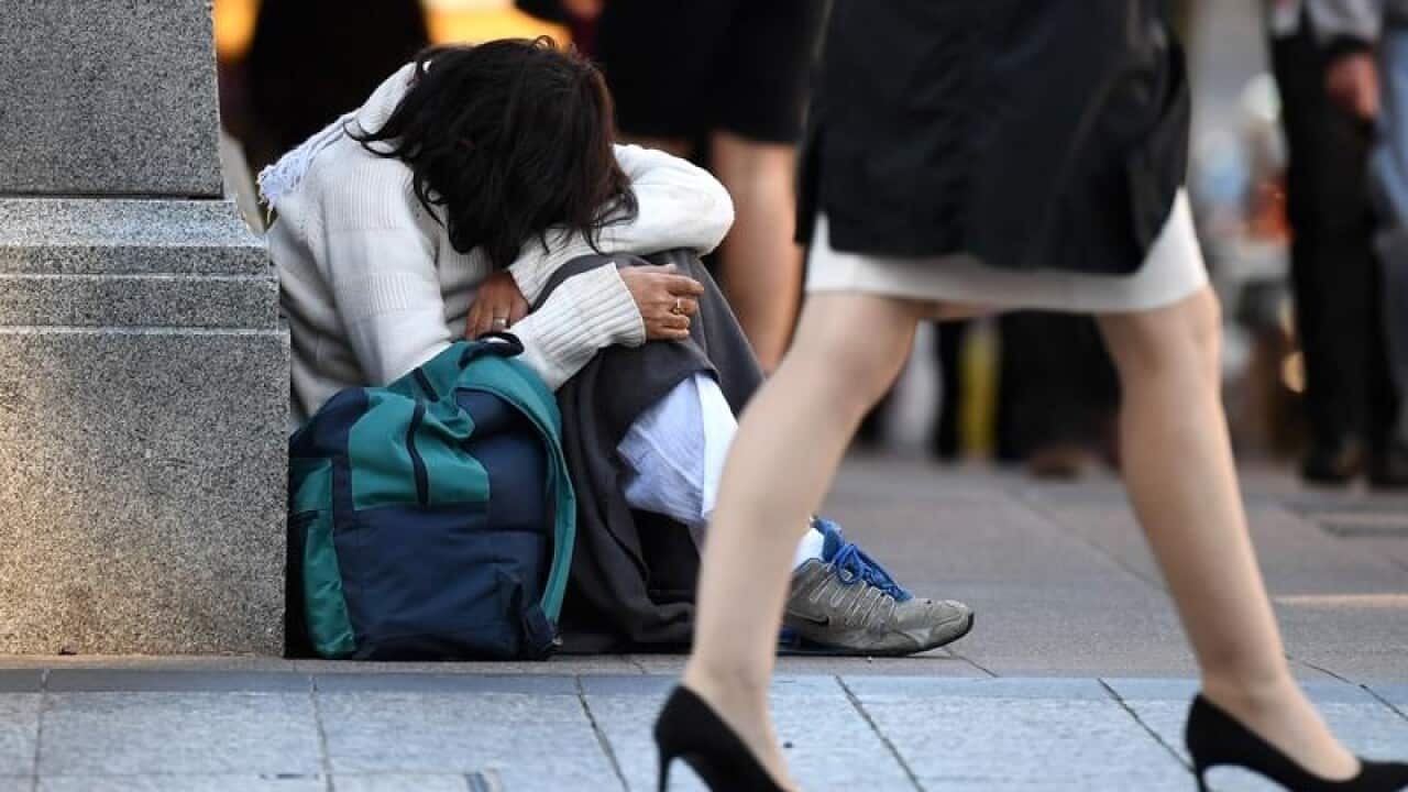 A homeless woman sits in the street in Brisbane.