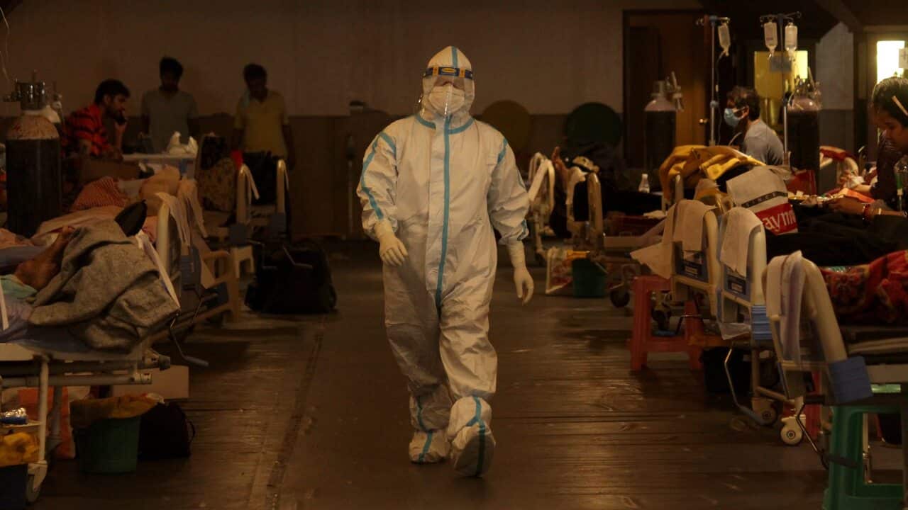 A health worker takes care of patients inside a banquet hall, temporarily converted into a quarantine facility for COVID-19 patients, in New Delhi on 4 May.