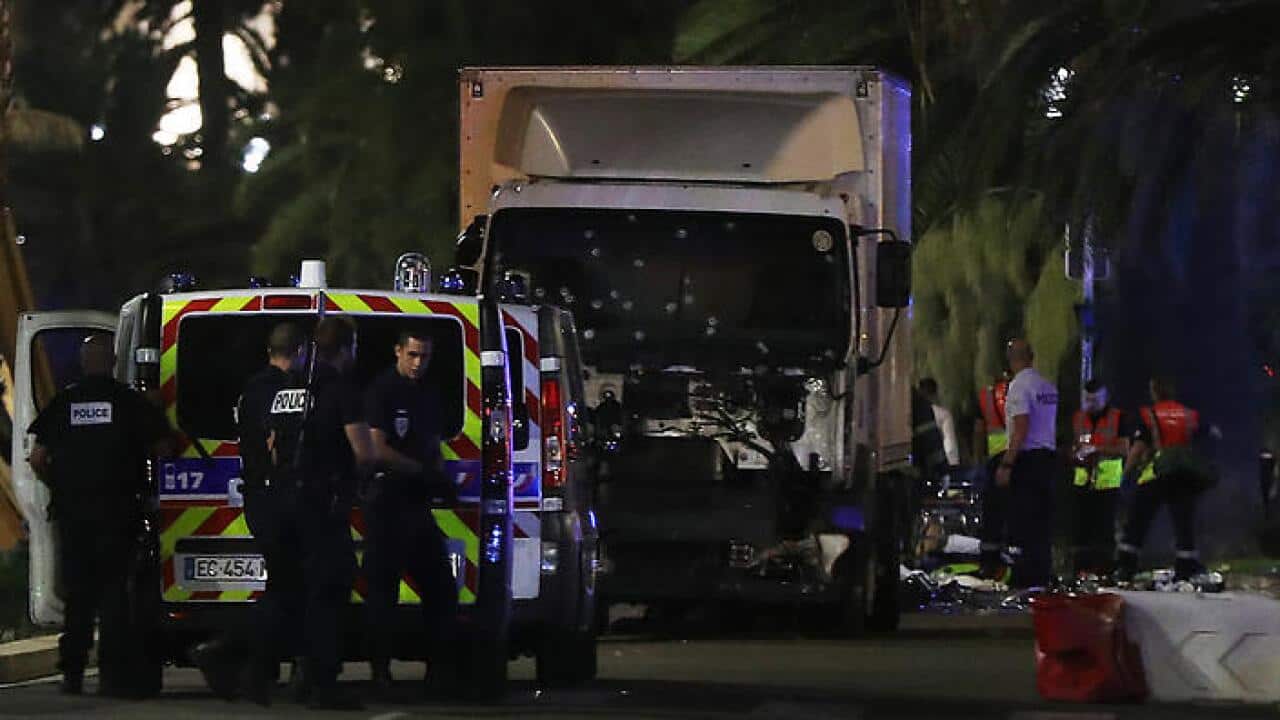 Police officers and rescue workers stand near a van that ploughed into a crowd leaving a fireworks display in the French Riviera town of Nice on July 14, 2016.The mayor of the French city of Nice said dozens of people were likely killed after a van rammed