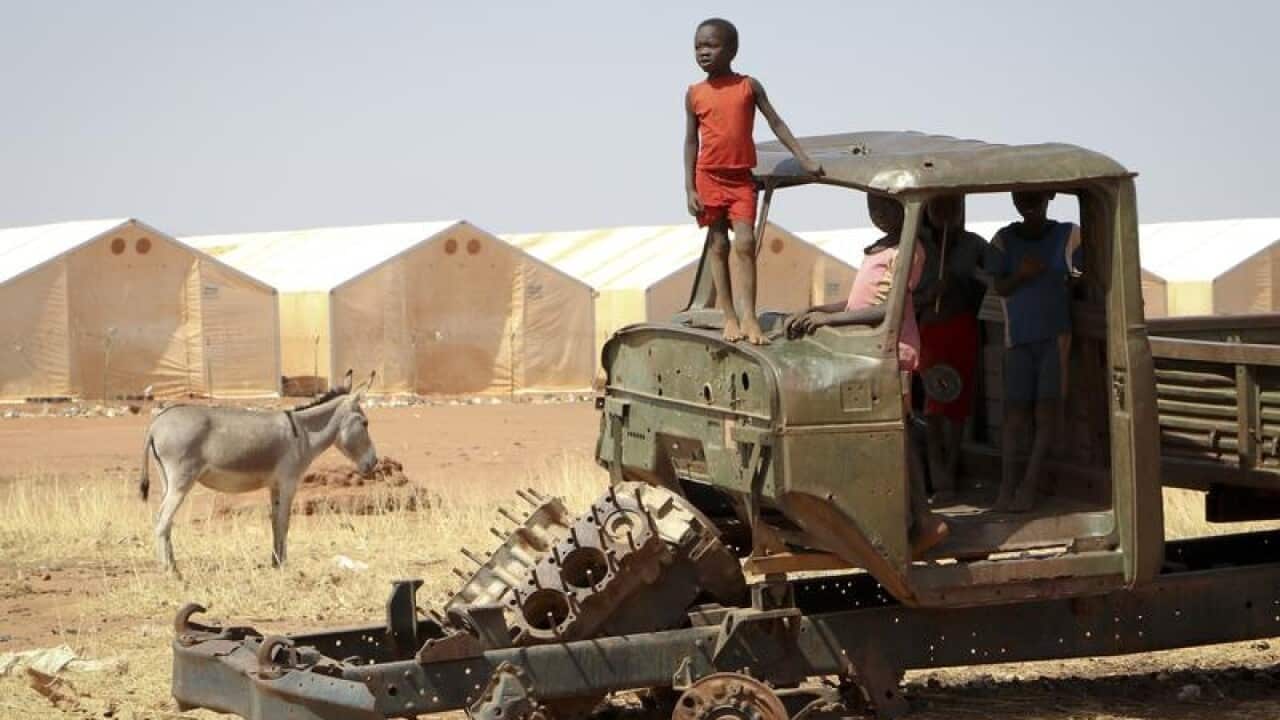 A Sudanese refugee boy on top of a broken-down tractor