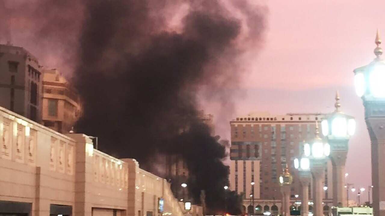 In this photo provided by Noor Punasiya, people stand by an explosion site in Medina, Saudi Arabia