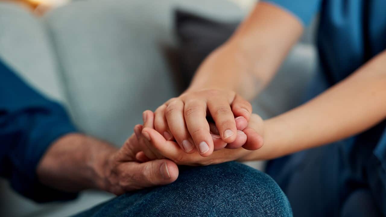 Hand holding, caregiver and man on sofa with elderly care, support or checkup in rehabilitation. Closeup, healthcare and nurse in home with consultation, trust or medical service in retirement.