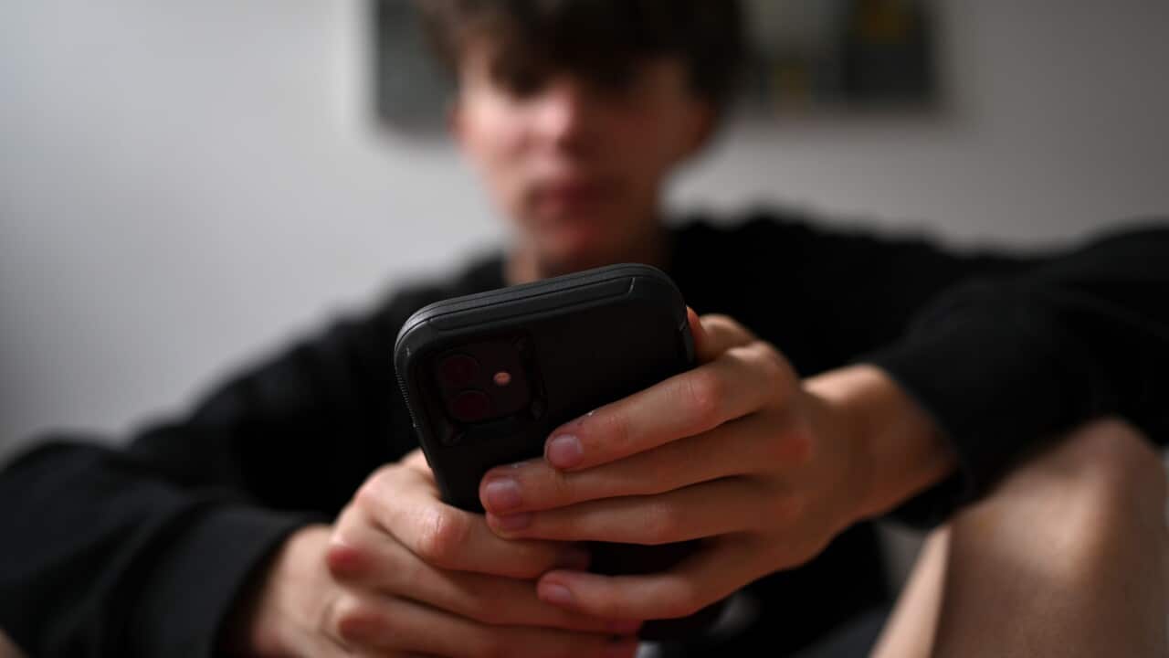 A teenager uses his mobile phone to access social media