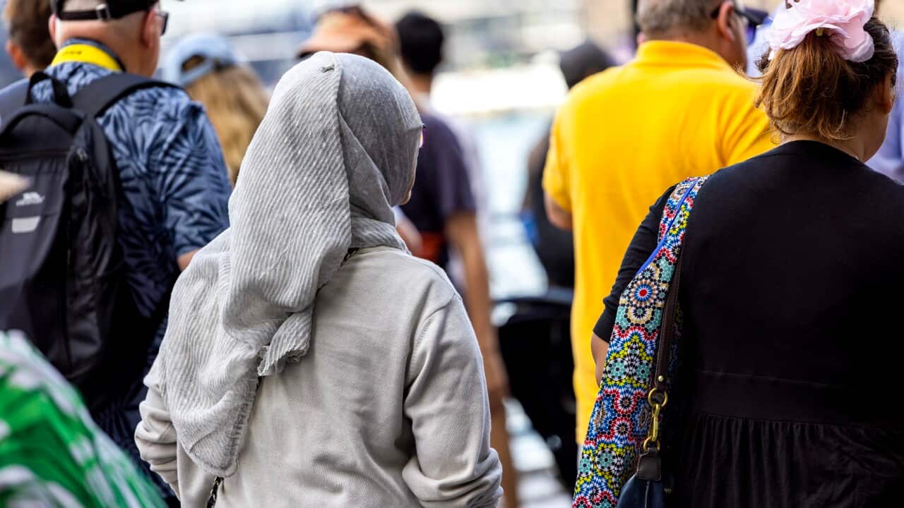 Rear view of woman wearing hijab walking in crowd of people, background with copy space