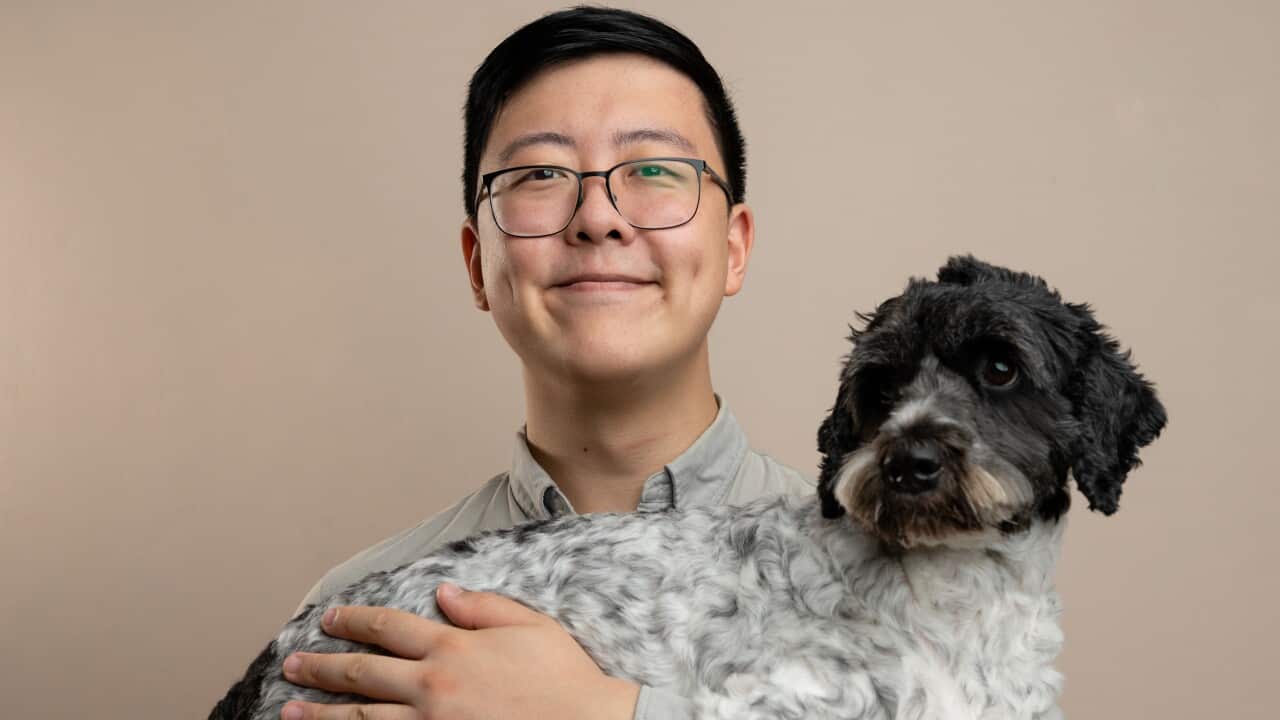 Young man with glasses holding dog