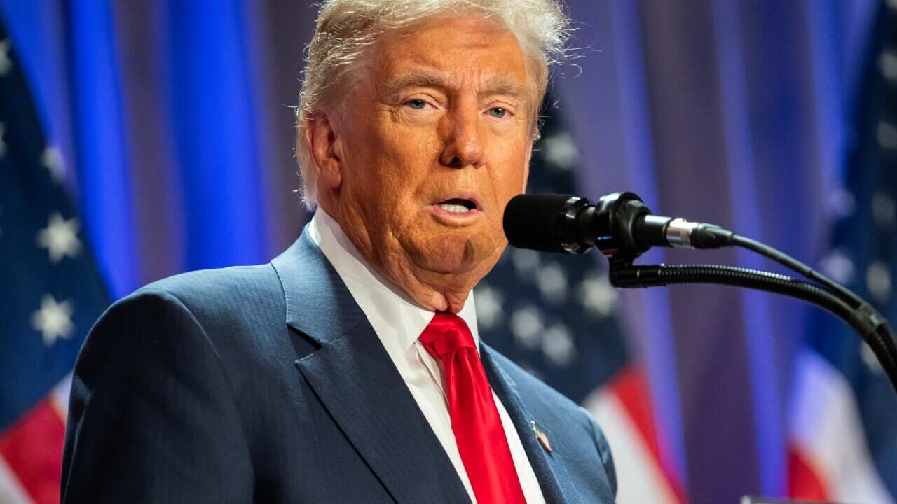A man in a dark suit stands at a podium
