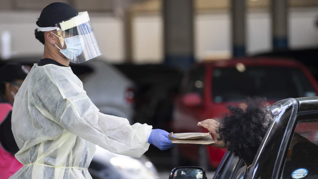 A health worker gives out Rapid Covid-19 antigen self-test kits at the Waipareira Trust drive-in COVID-19 testing station in Auckland.