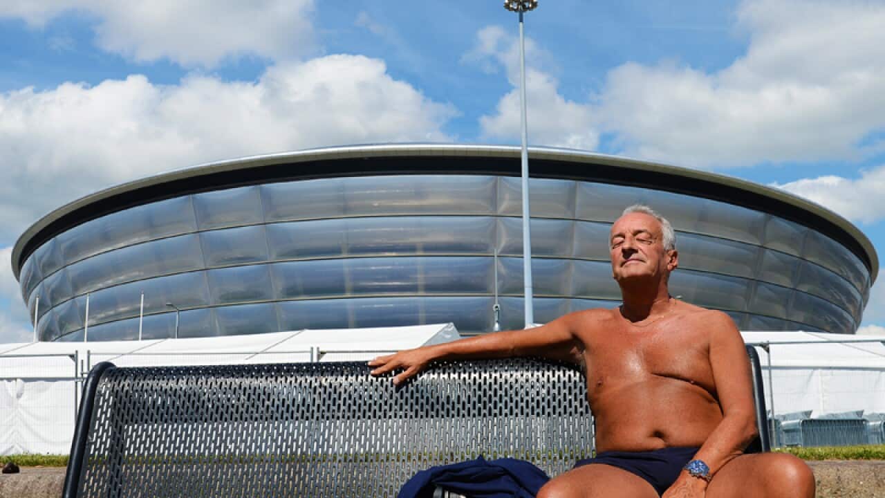 A man basks in te warm weather outside a Commonwealth Games venue