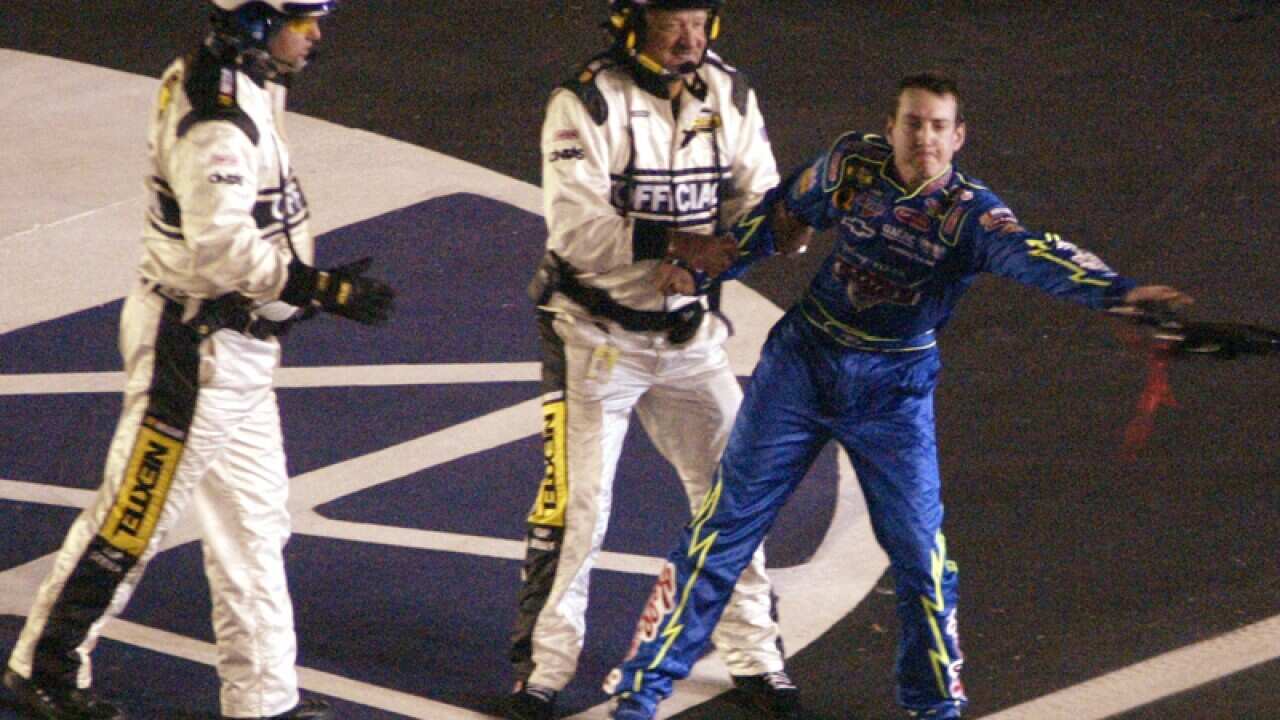 driver Kyle Busch is restrained by a NASCAR official