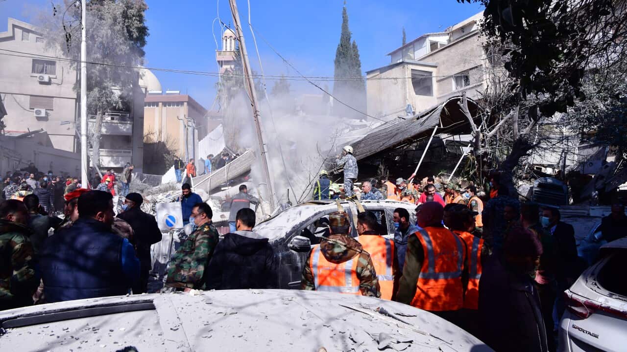 People standing around the rubble of destroyed buildings.