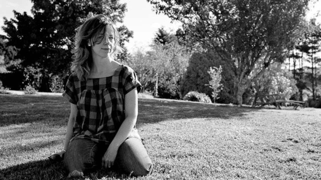 Black and white photo of woman sitting in a park.