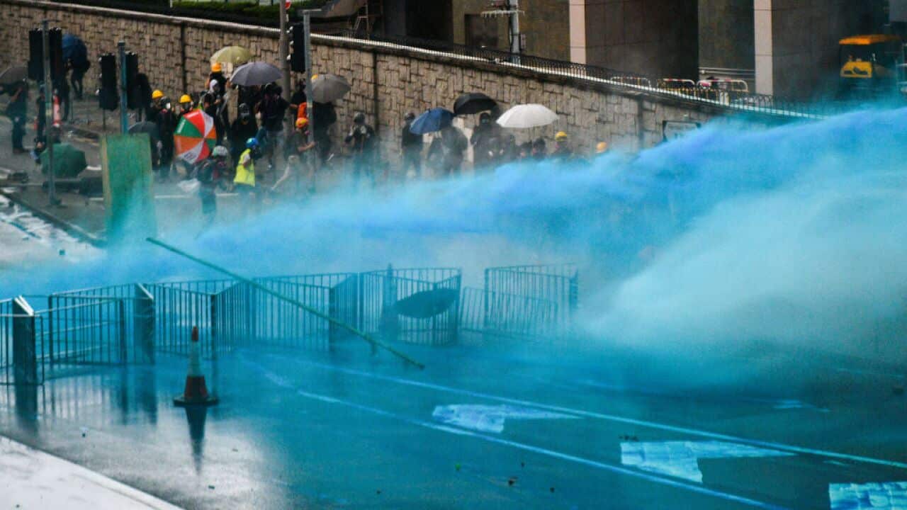 Police fire a water cannon filled with blue dye at protesters outside the government headquarters in Hong Kong.