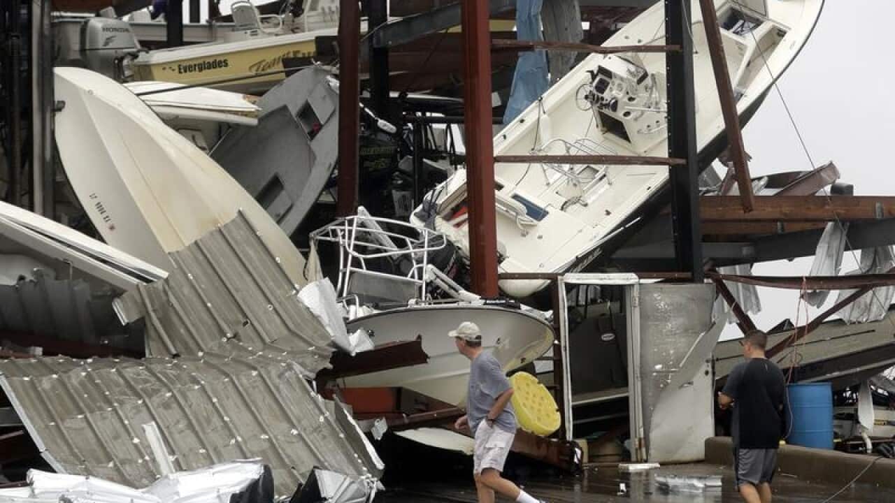 People walk past a damaged boat storage facility in Rockport, Texas