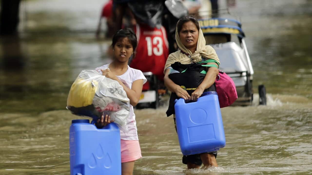 Filipino villagers manoeuvre through floodwaters