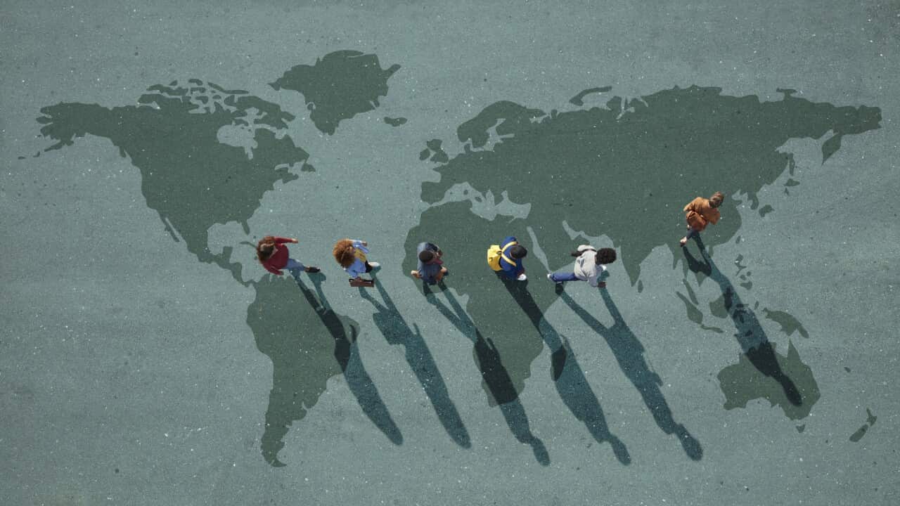 People walking in line across world map, painted on asphalt, front person walking left