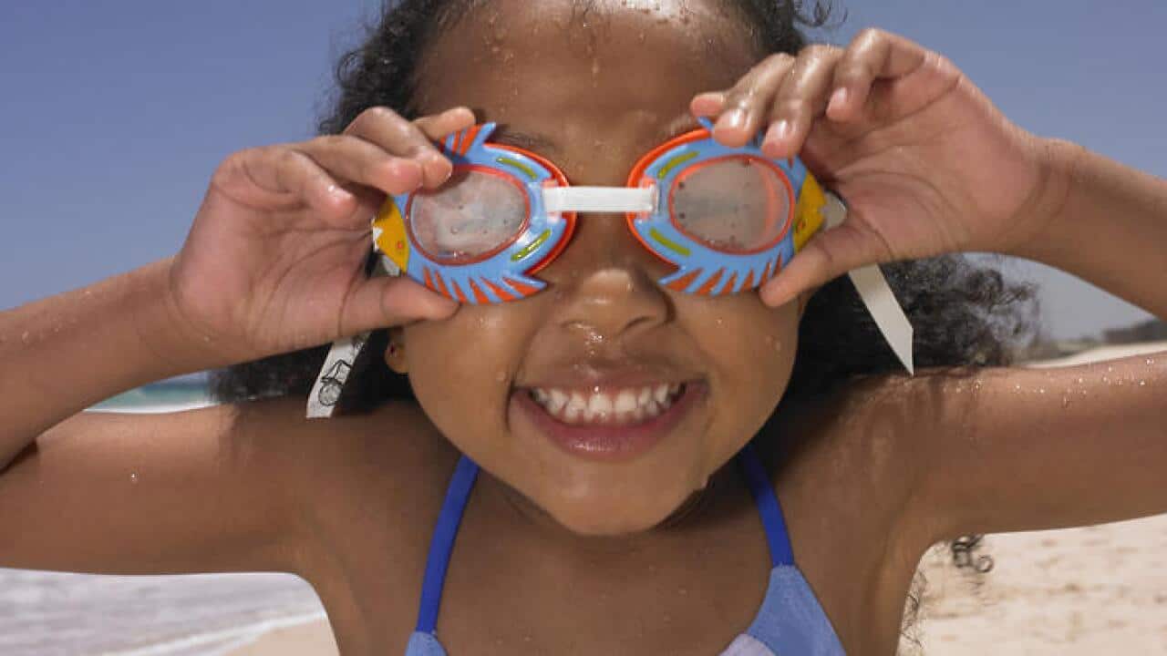 Smiling girl wearing goggles at beach